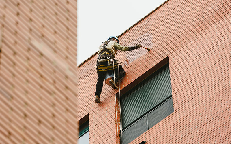 Eine Person reinigt die Fassade eines Gebäudes