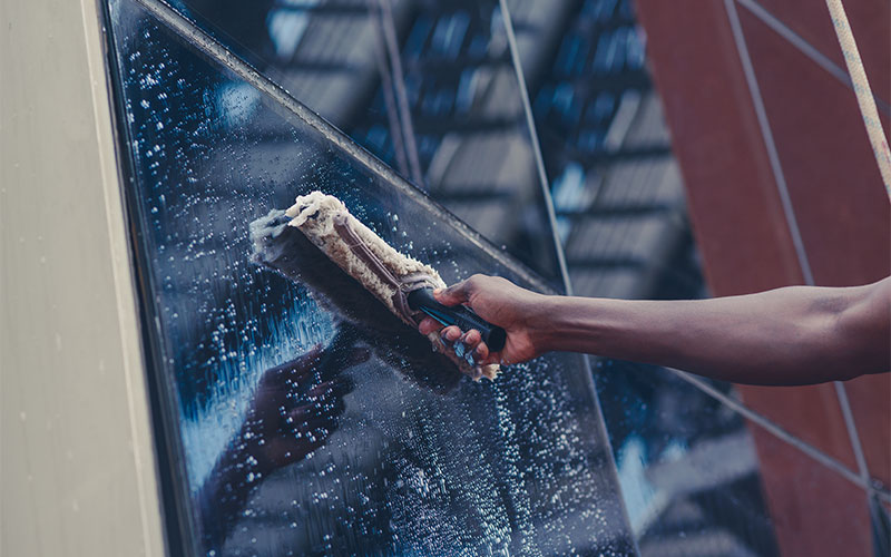 Eine Person reinigt Fassadenglas