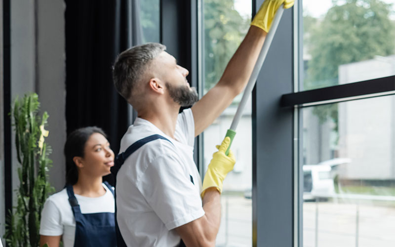 Mehrere Personen reinigen eine Fensterscheibe von innen